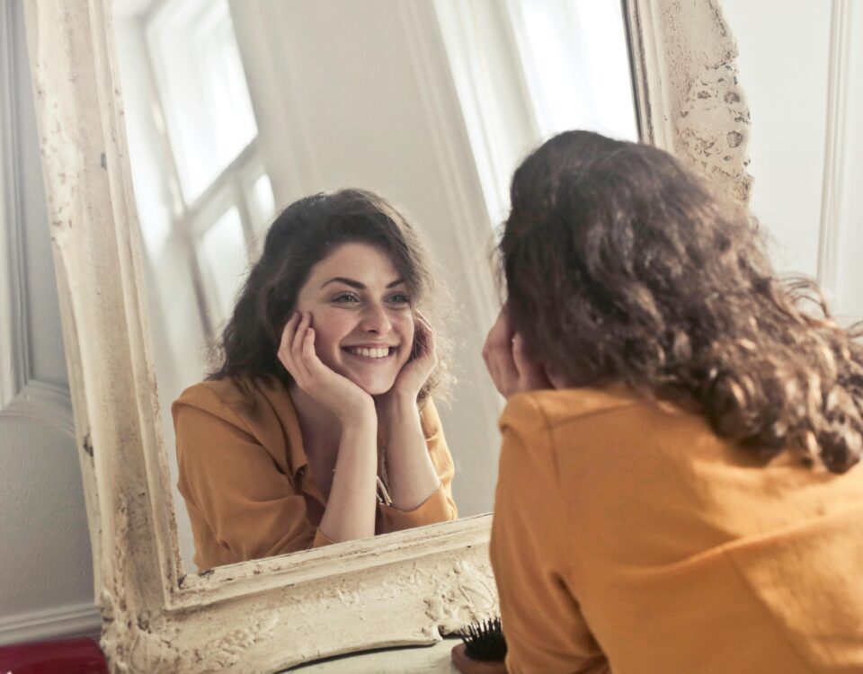 Mujer mirándose al espejo en una imagen sobre autoexigencia y perfeccionismo.